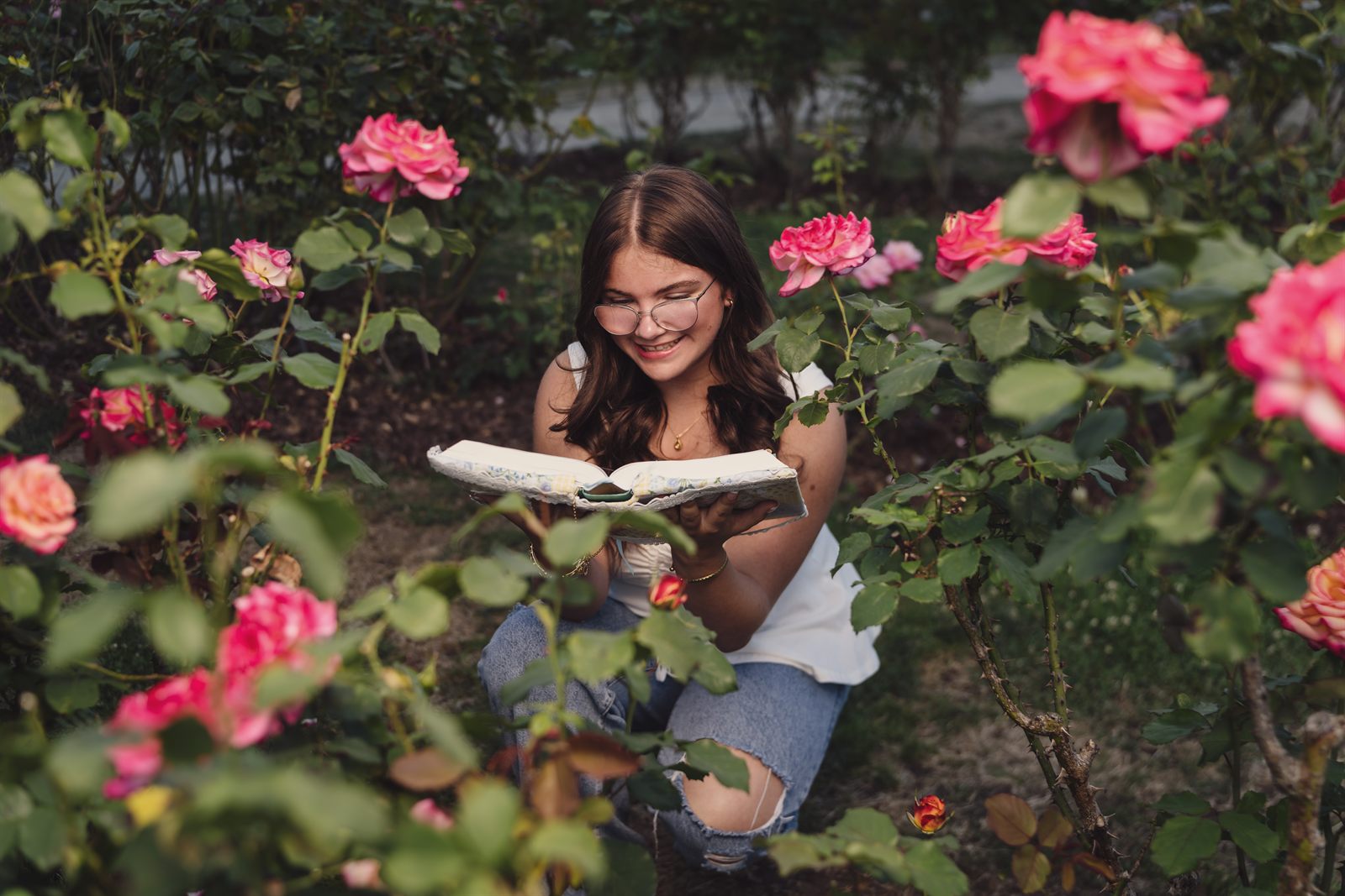 Teen reading a book among pink roses at Point Defiance Rose Garden in Tacoma