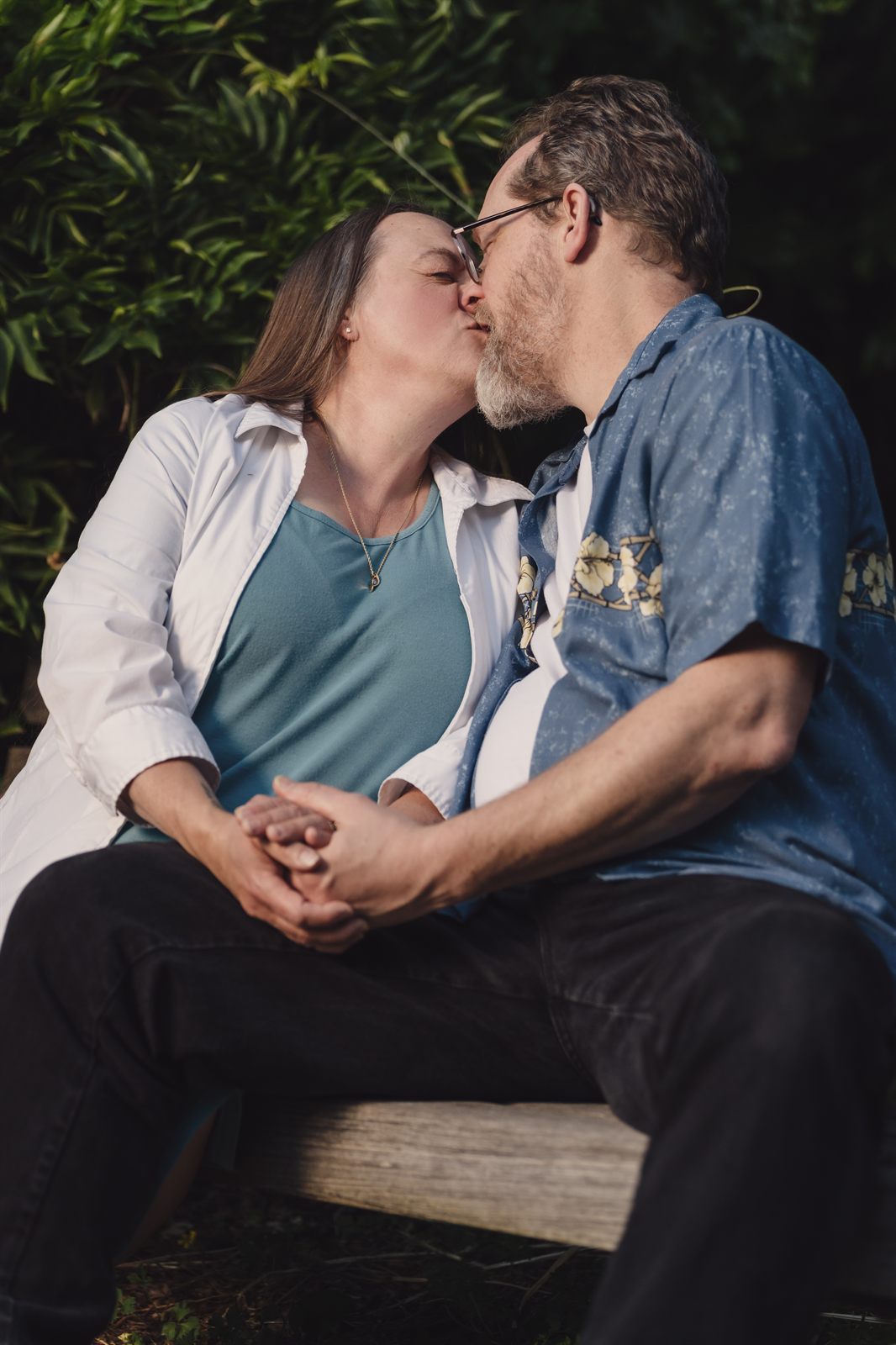 Parents sitting close on a garden bench at golden hour at Point Defiance Rose Garden in Tacoma
