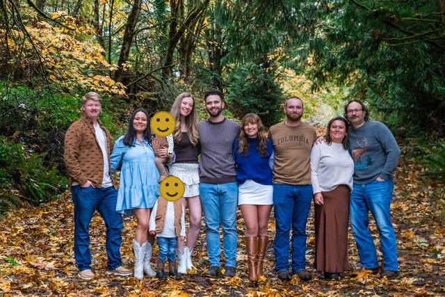 Large extended family on a leaf covered path during a fall family photo session in Washington, faces covered for privacy