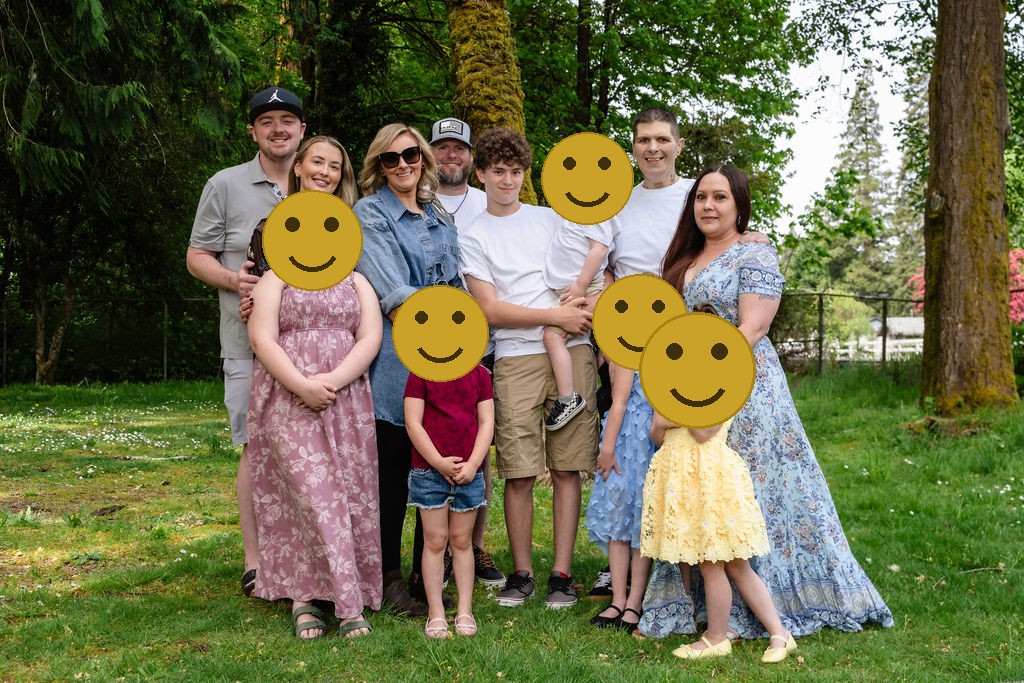 Large extended family posing together with their children among the trees at a Kitsap County park