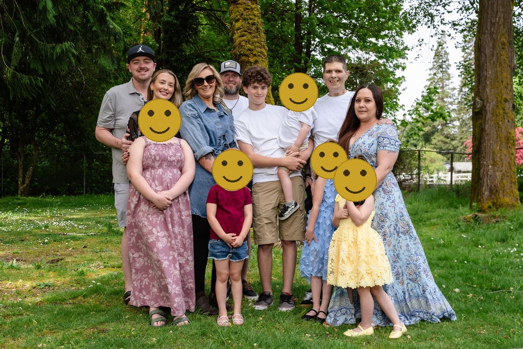 Large extended family posing together with their children among the trees at a Kitsap County park