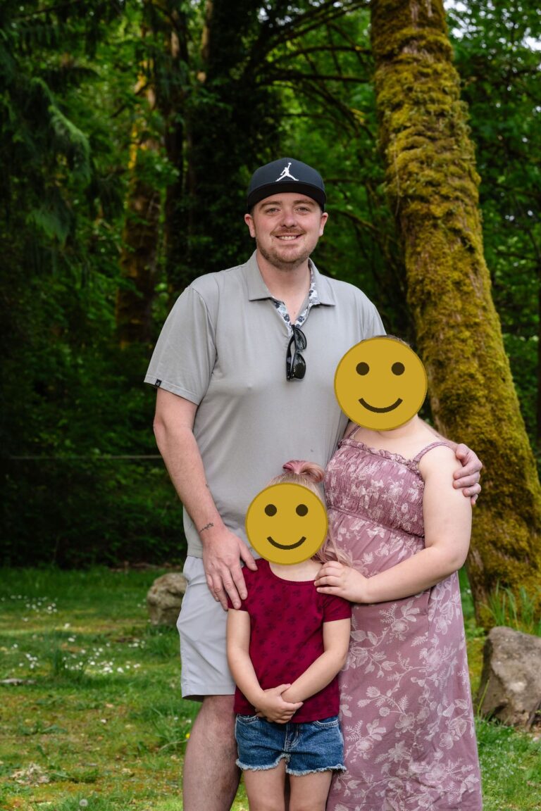 Father with his two daughters posing by a mossy tree at a green Kitsap County park