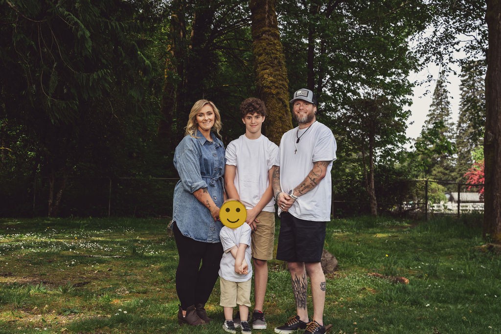 Family of four standing together under the trees at a Kitsap County park