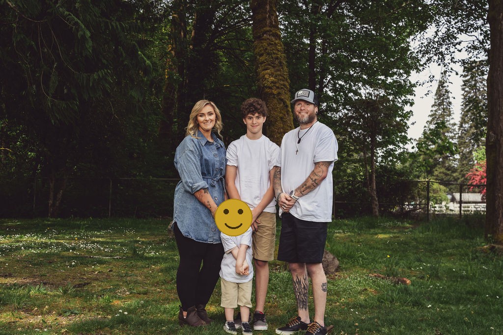 Family of four during an outdoor family photo session under the trees at a Kitsap County park in Washington, faces covered for privacy