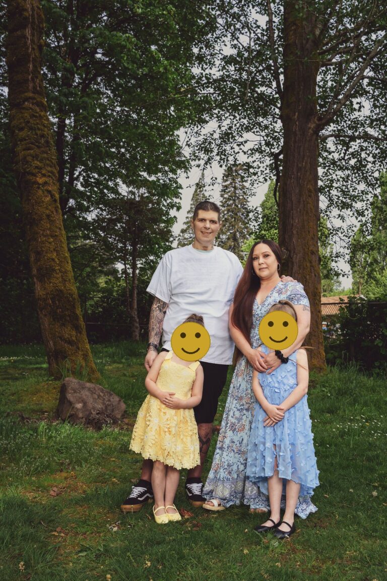 Family with two daughters and their small dog posing among the trees at a green Kitsap County park