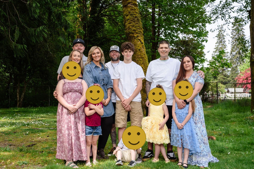 Large extended family gathered together at a green Kitsap County park, faces covered for privacy