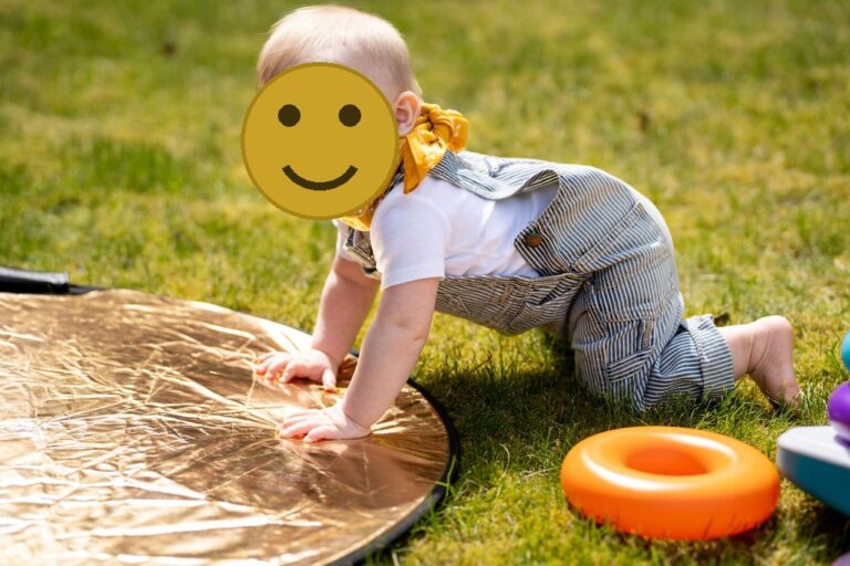 Baby in striped overalls crawling across the grass during an outdoor spring family session in Kitsap County