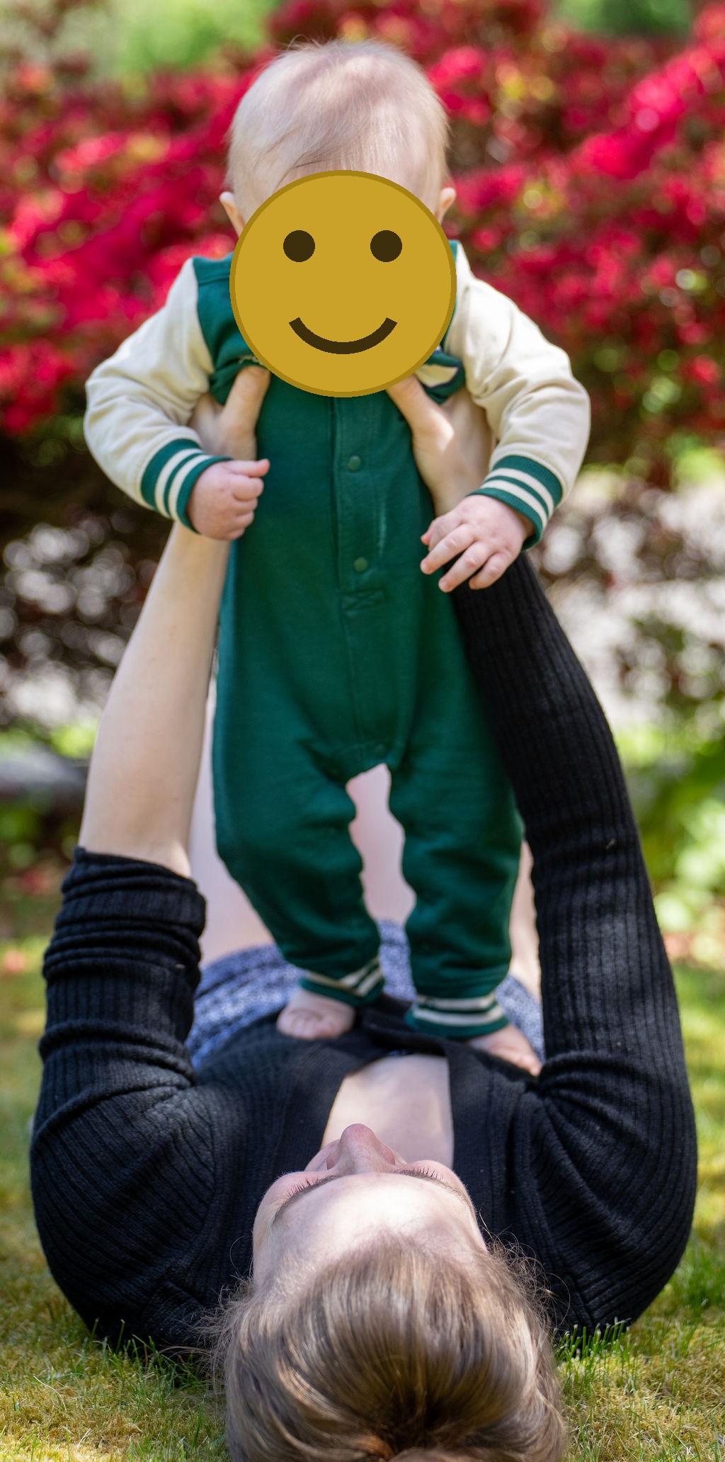 Mother lying in the grass lifting her baby during an outdoor family session in Kitsap County