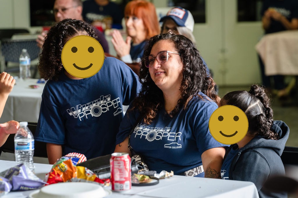 A mother and her daughters seated together with food at the Tacoma charity car giveaway