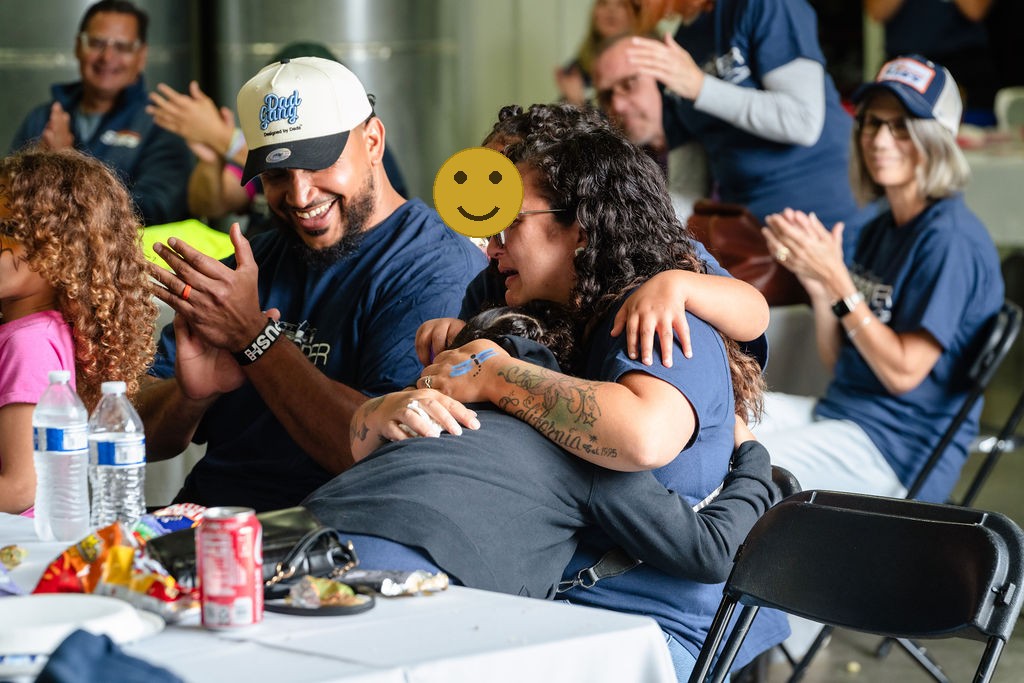 Local business owners applaud as the family embraces after learning they won the car