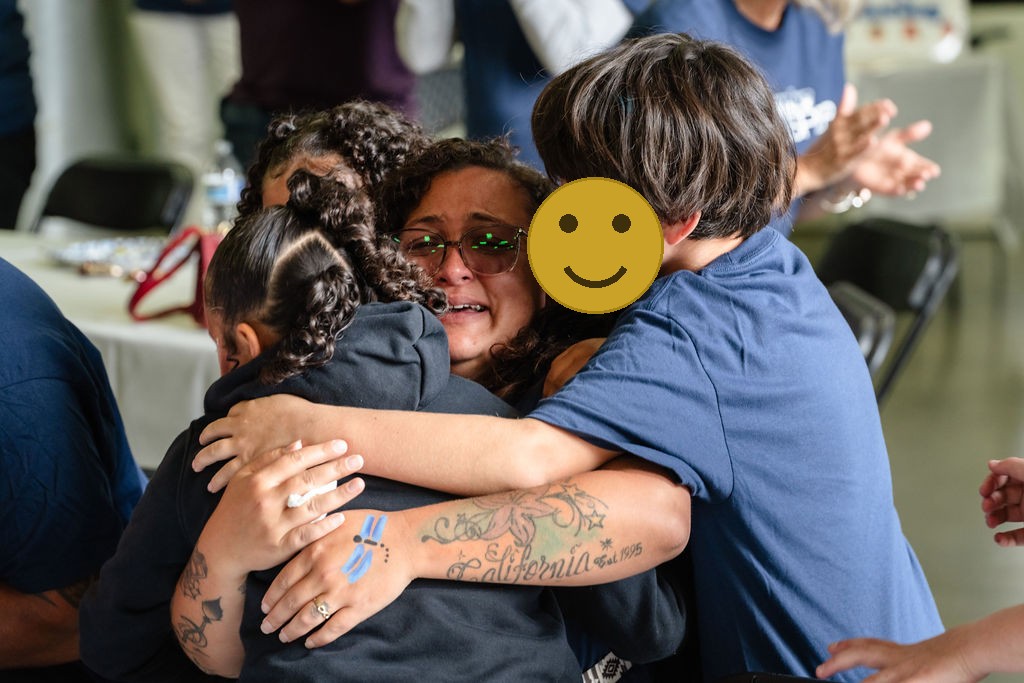 A tearful mother held by her children at the Tacoma charity car giveaway
