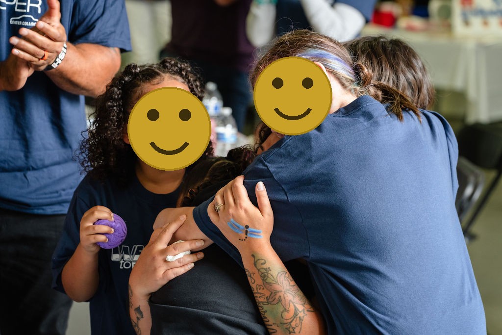 A smiling daughter beside relatives hugging during the Tacoma community car donation event