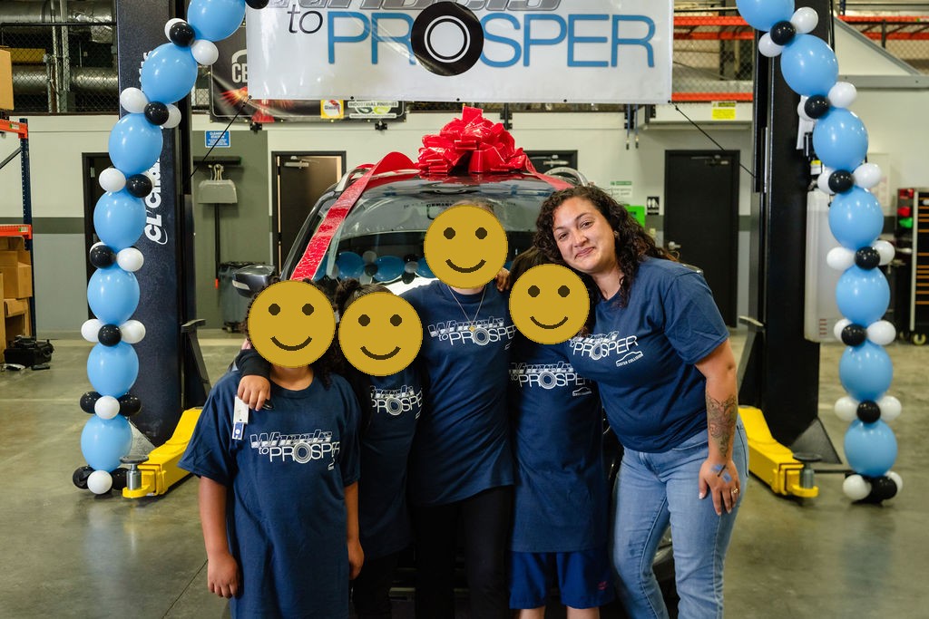 Family hugging under a balloon arch beside their new car at a community event
