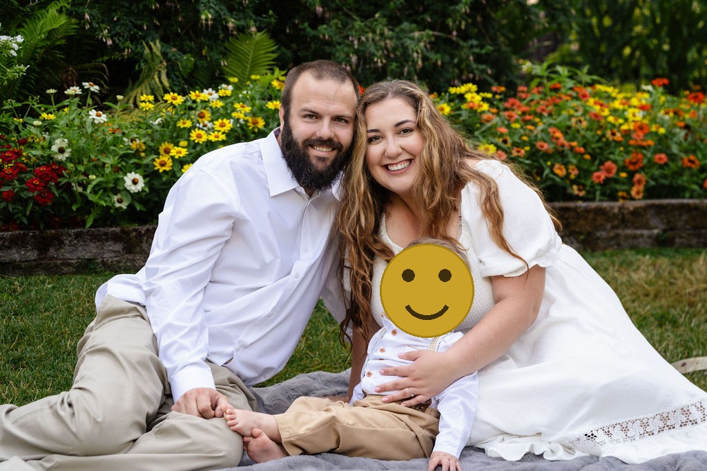 Parents and their baby son smiling on a picnic blanket at the Point Defiance Rose Garden in Tacoma