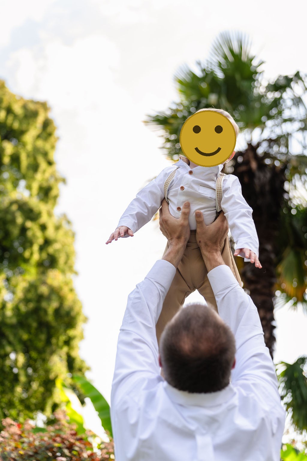 Little boy laughing as his dad lifts him skyward in the gardens at Point Defiance in Tacoma