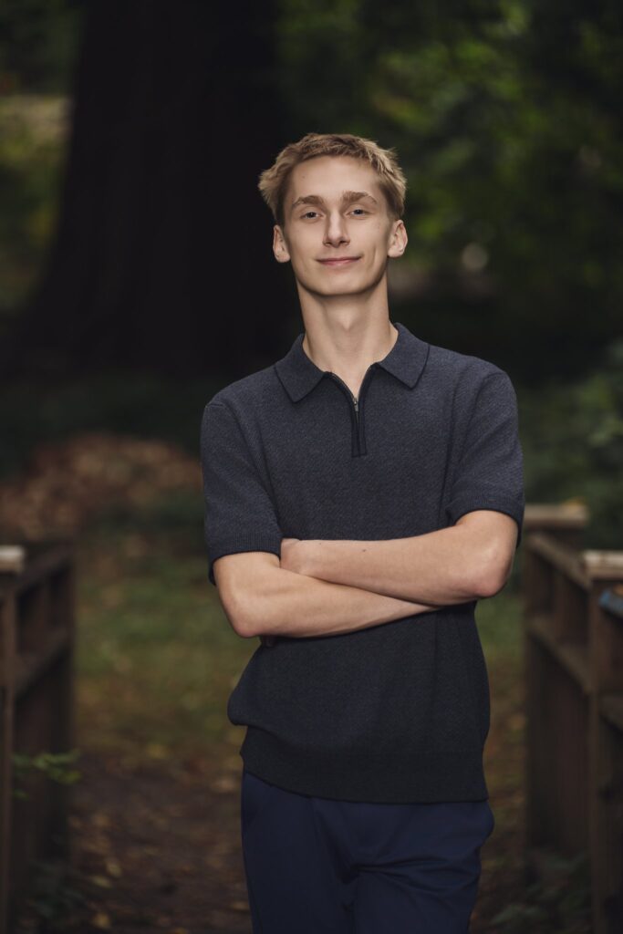 High school senior with arms crossed on a wooden footbridge at Smith Childrens Park in Bremerton