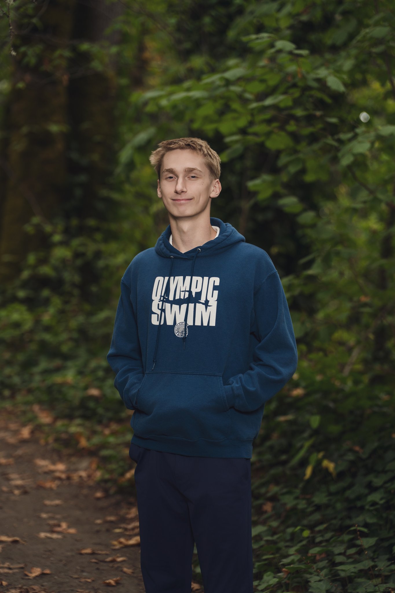 High school senior in an Olympic Swim hoodie on a forest trail at Smith Childrens Park in Bremerton