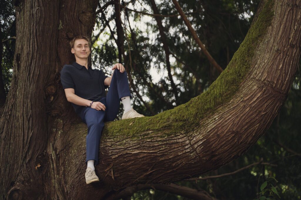 High school senior perched on a mossy tree limb at J.A. and Anna F. Smith Childrens Park in Bremerton