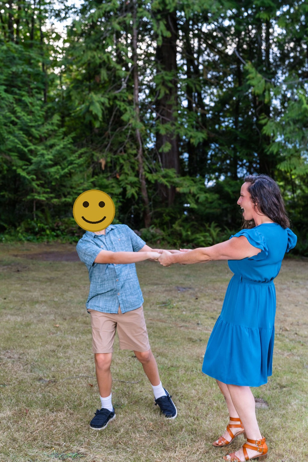 Mother and son laughing and dancing together during an outdoor family photo session in a grassy clearing in Washington