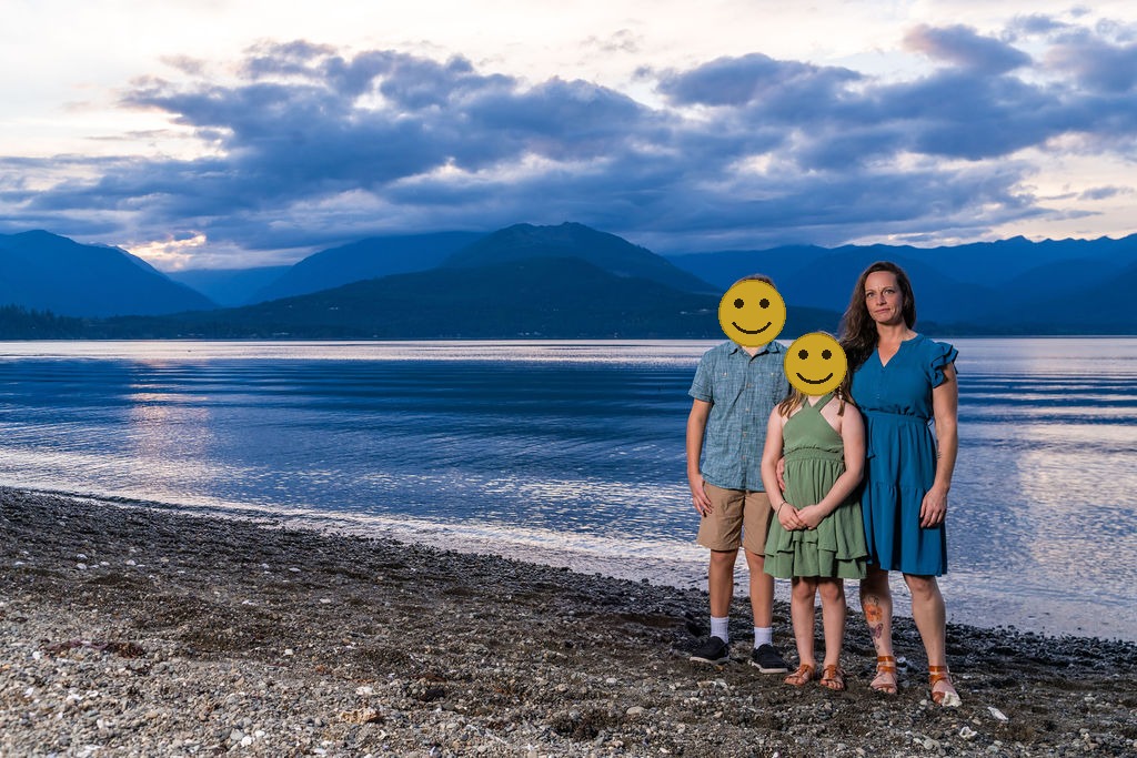 Family photo session with a mother, son and daughter on the shoreline at dusk in Washington, faces covered for privacy