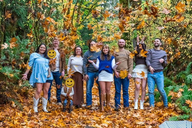 Extended family tossing autumn leaves together in coordinated neutral outfits during a fall family photo session in Washington