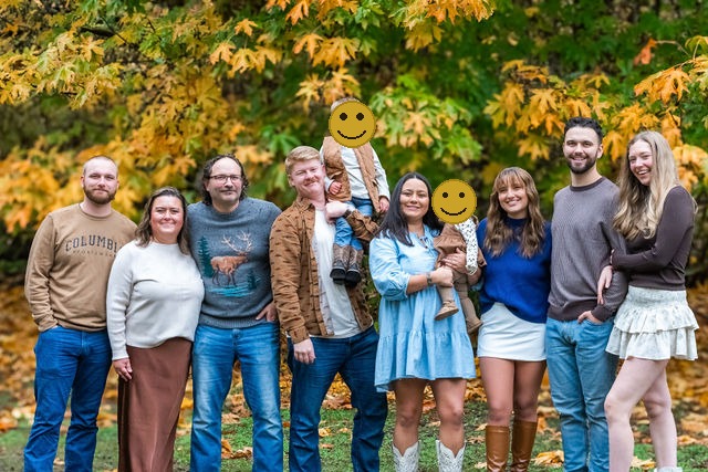 Large extended family portrait in fall foliage during an outdoor family photo session in Washington, faces covered for privacy