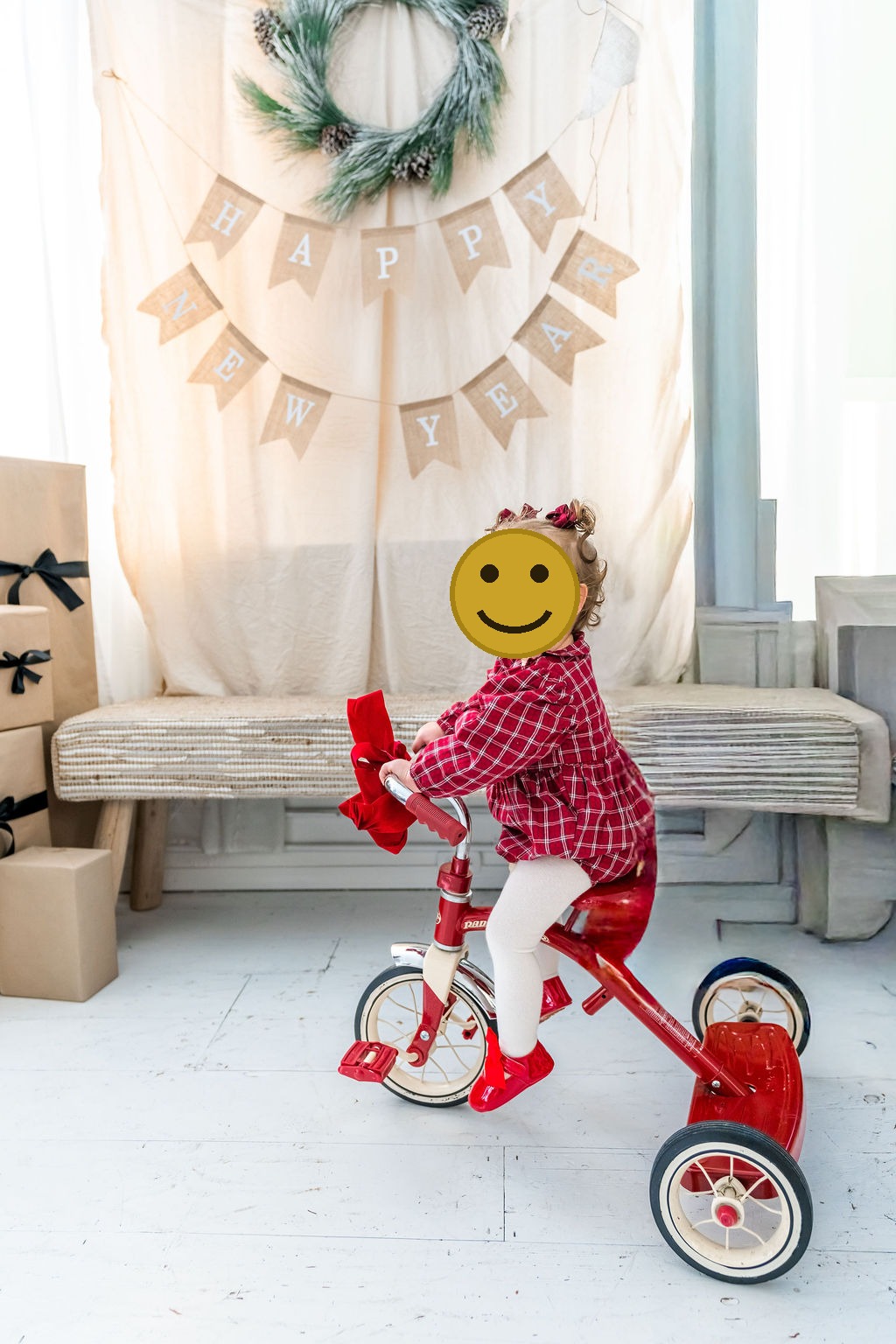 Toddler girl in a red plaid dress on a red tricycle during an indoor family studio session in Washington