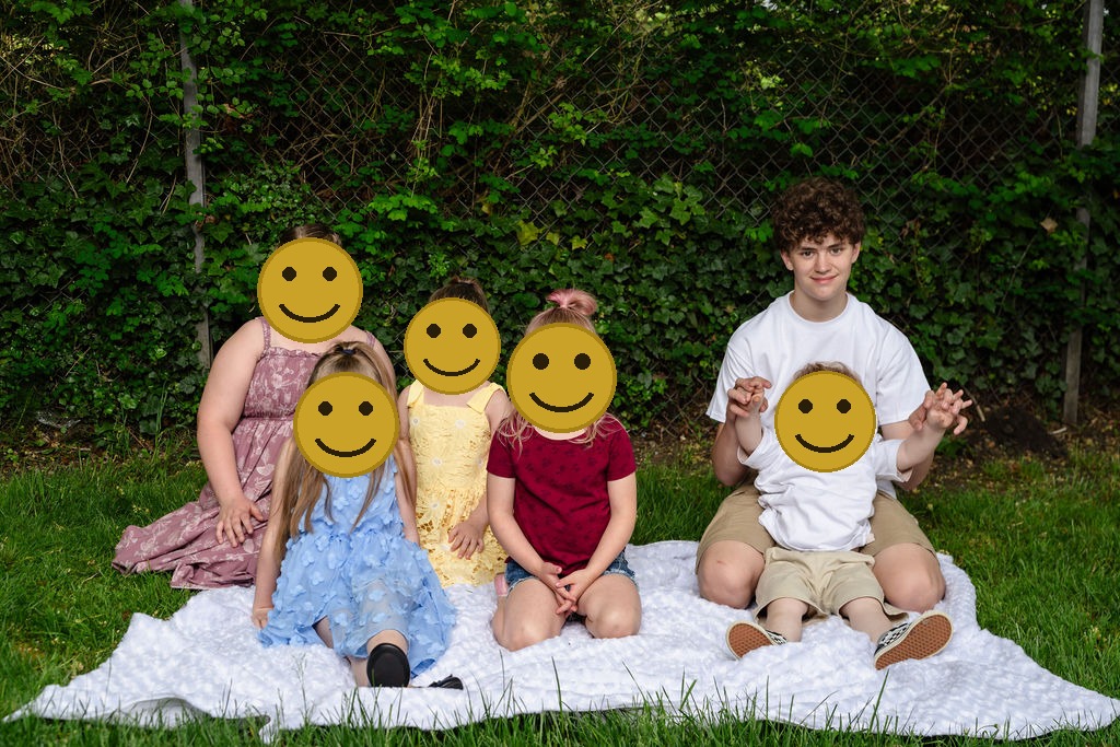 Group of children sitting together on a blanket at a Kitsap County park, faces covered for privacy