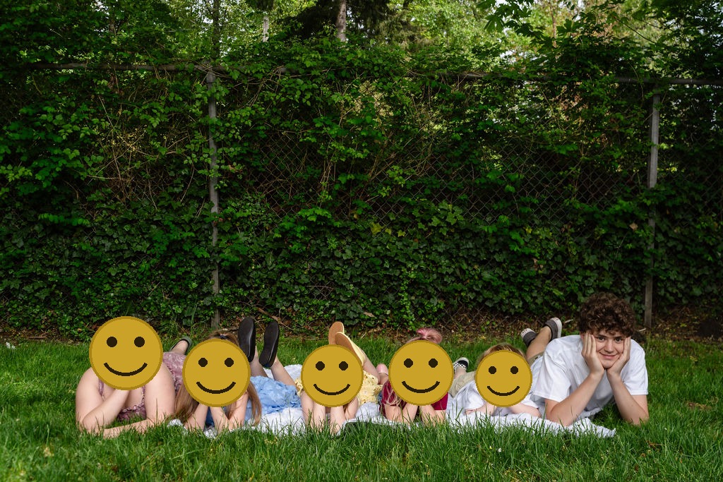 Six children lying in a row in the grass during a family photo session at a Kitsap County park in Washington