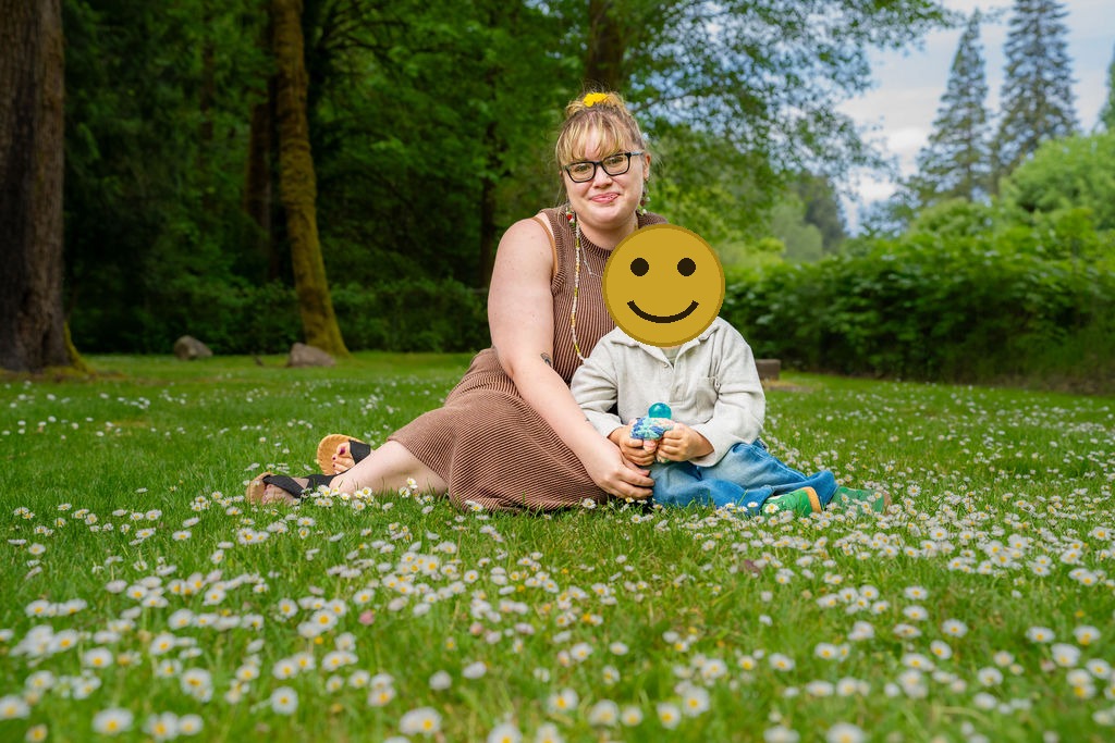Mother and son sitting together in a daisy filled meadow at a Kitsap County park