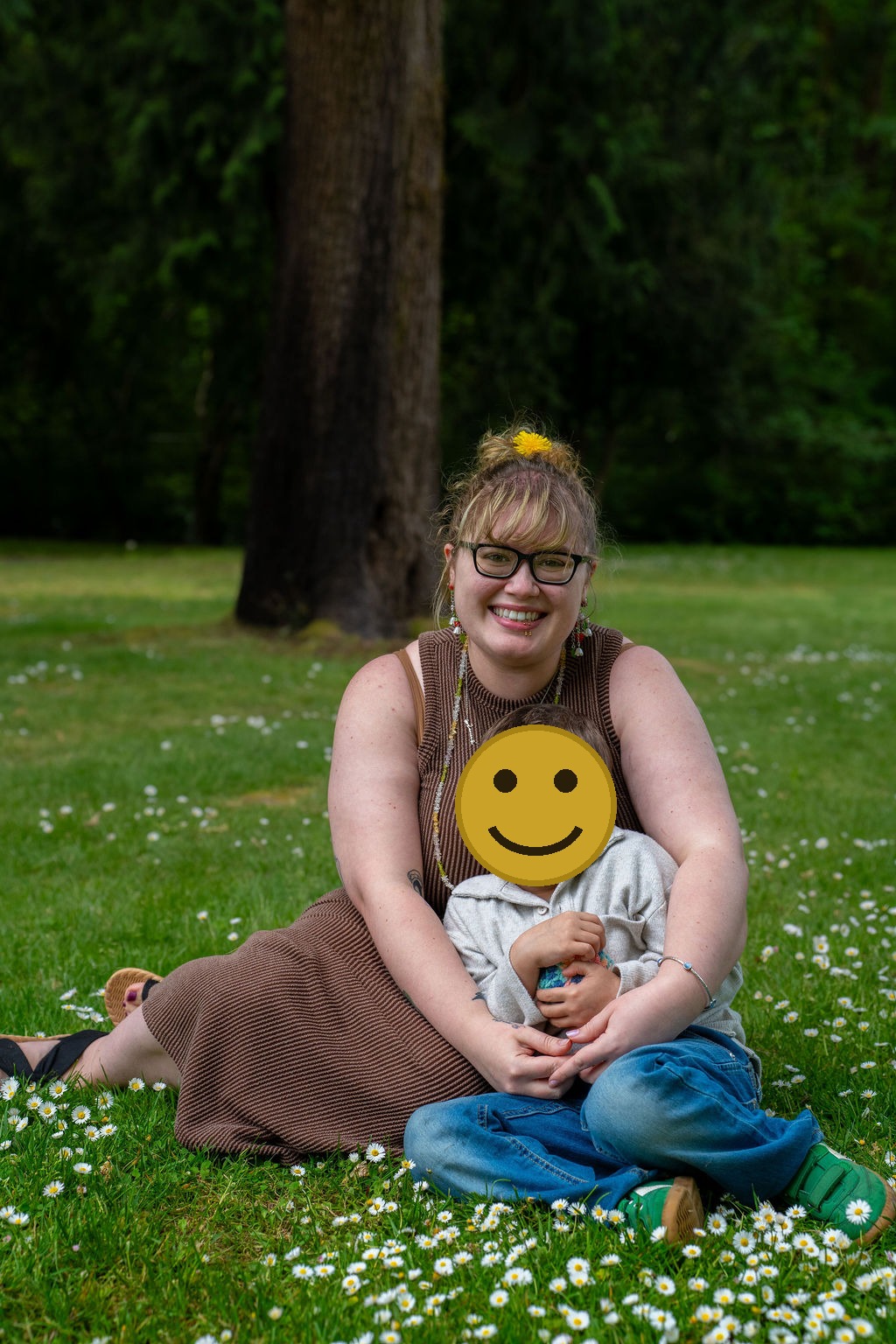 Family photo session with a mother and her son sitting in a daisy filled lawn at a park in Kitsap County, Washington