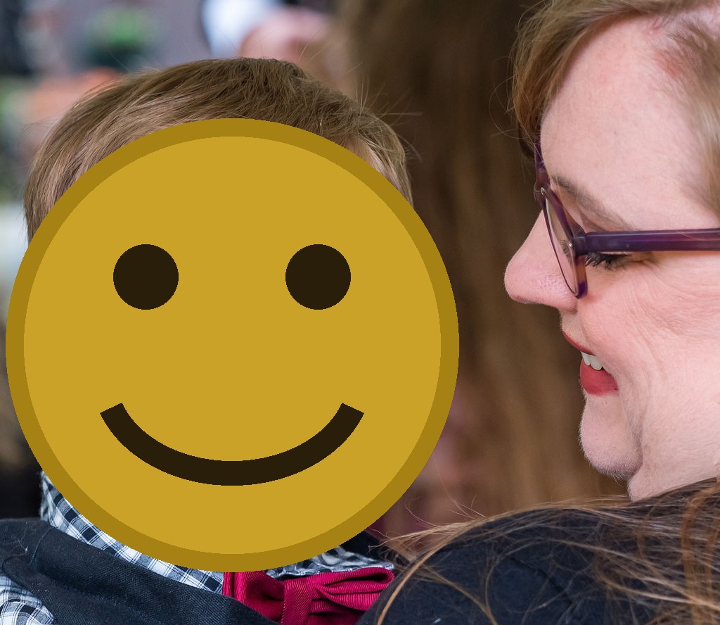 Young child with a bow tie smiling while being held by a guest during a Vashon Island wedding in Washington