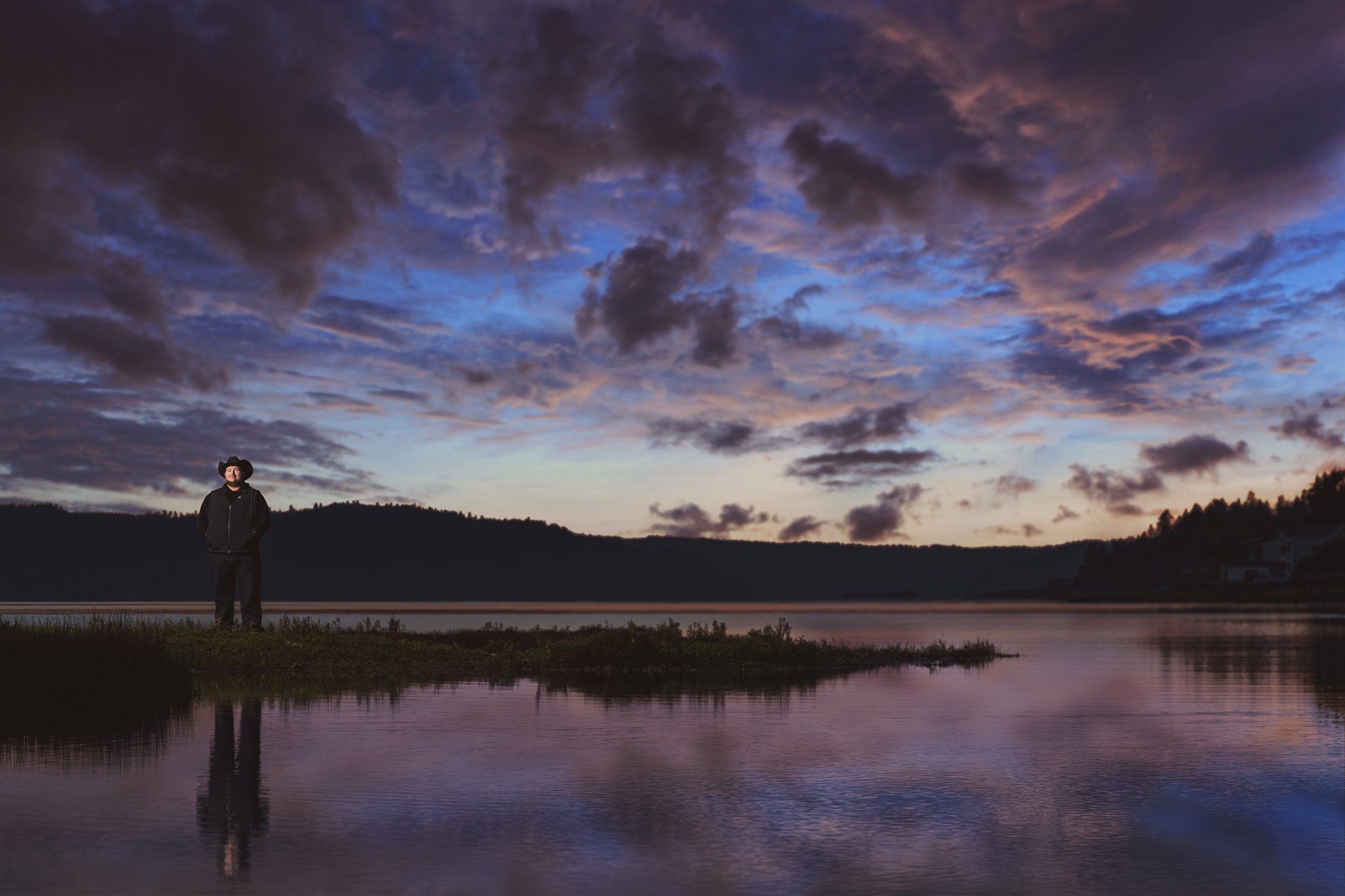 Belfair State Park senior pictures of a high school senior in a cowboy hat reflected in still water at blue hour on Hood Canal. Photographed by Nautical Moments Photography.
