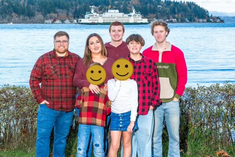 Family portrait beside Puget Sound in Washington with a Washington State Ferry crossing behind them