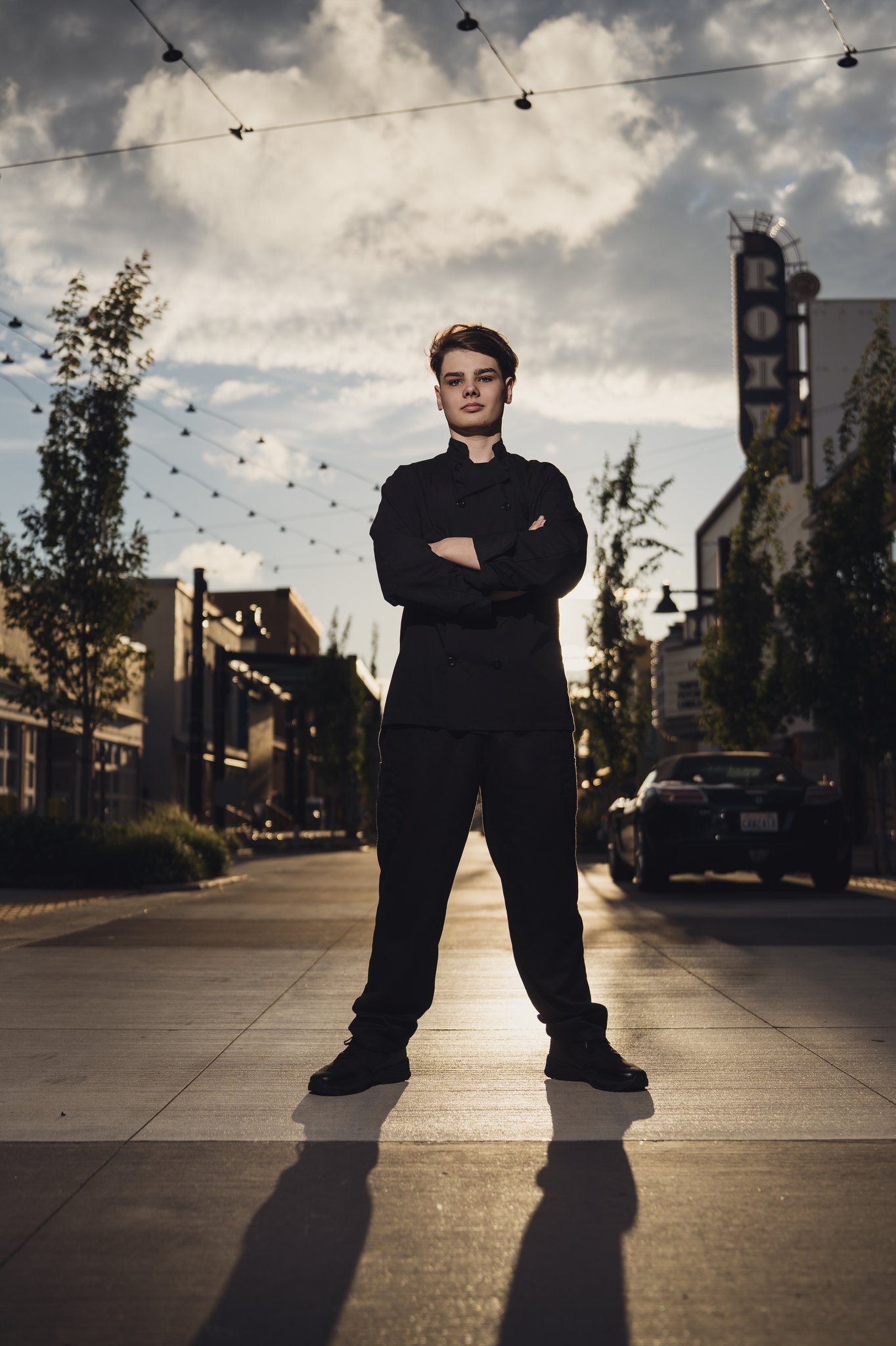 Downtown Bremerton senior pictures of a high school senior in a chef coat with the Roxy Theatre marquee behind him. Photographed by Bremerton senior photographer Nautical Moments Photography.